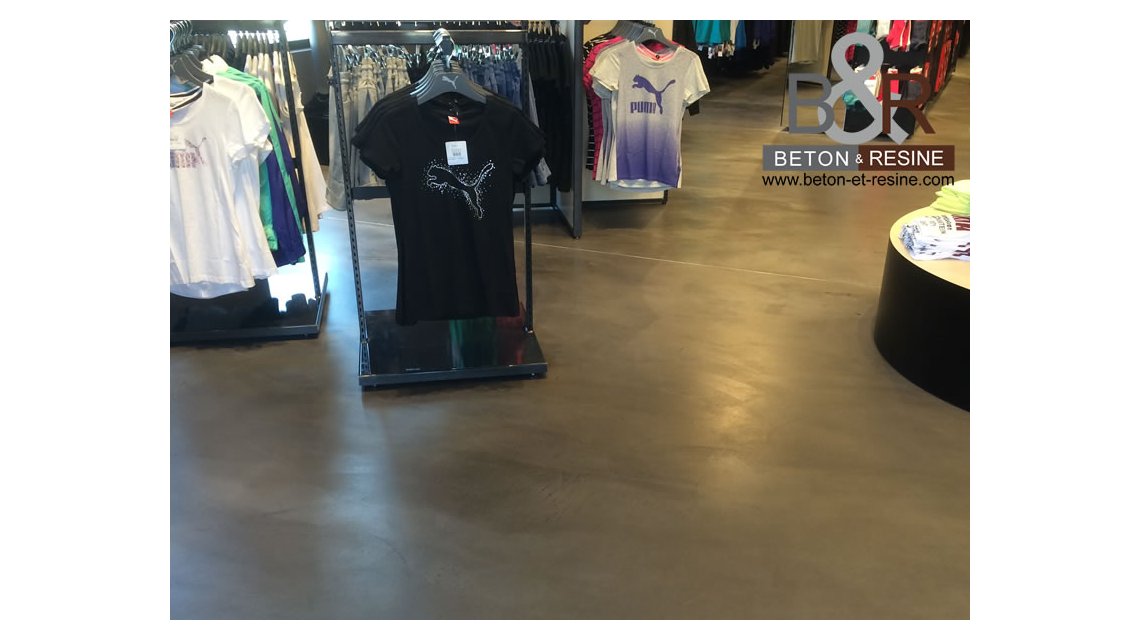 Chantier réalisé pour un Magasin Puma sur l'A13 : Marque Avenue Puma Outlet Aubergenville (78). C'est un béton ciré spatulé millimétrique gris anthracite, réalisé sur une grande surface de vente (280m2)   
